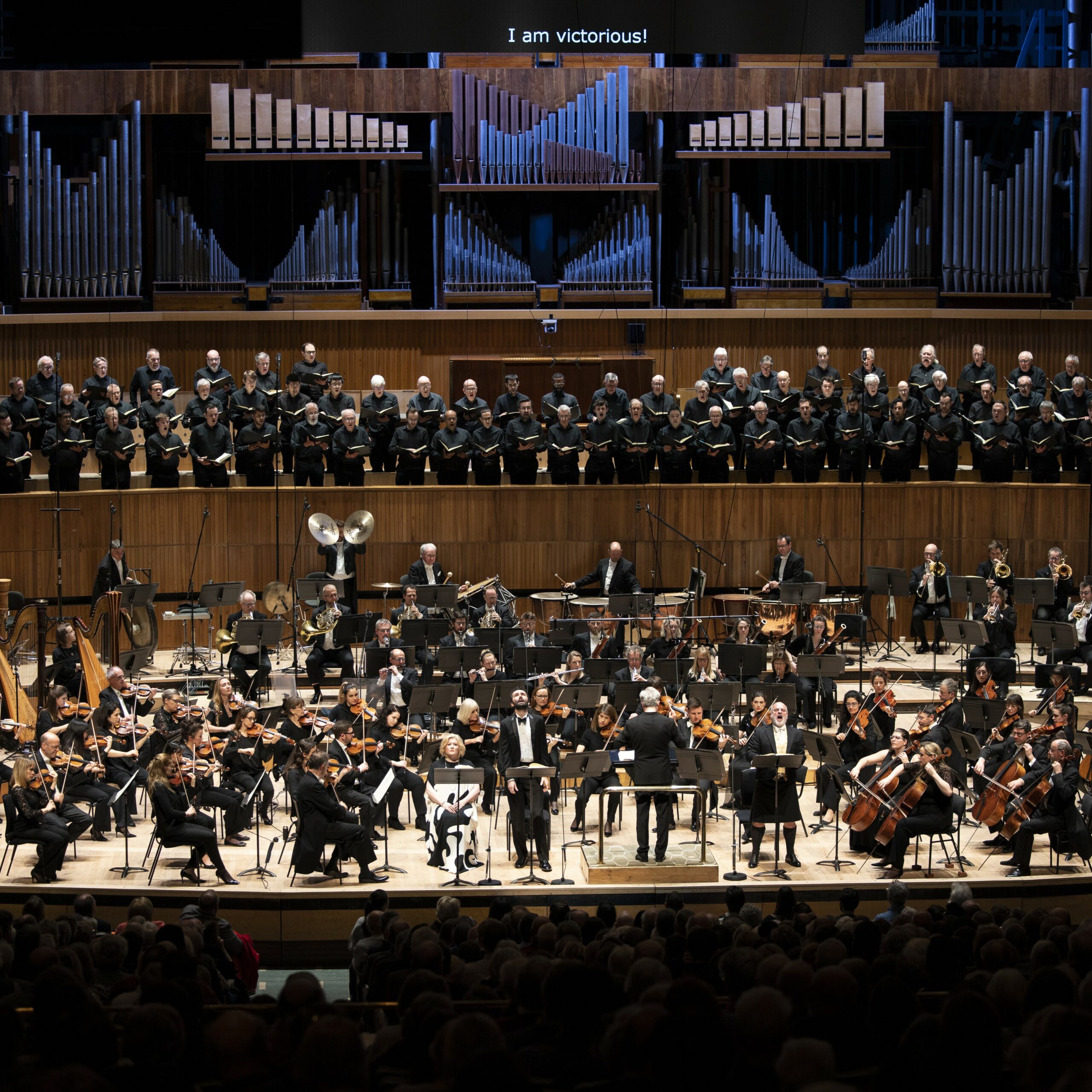 John Irvin, Christopher Purves, 5x5 A choir, orchestra, soloists and conductor on stage at the Royal Festival Hall, wearing black.