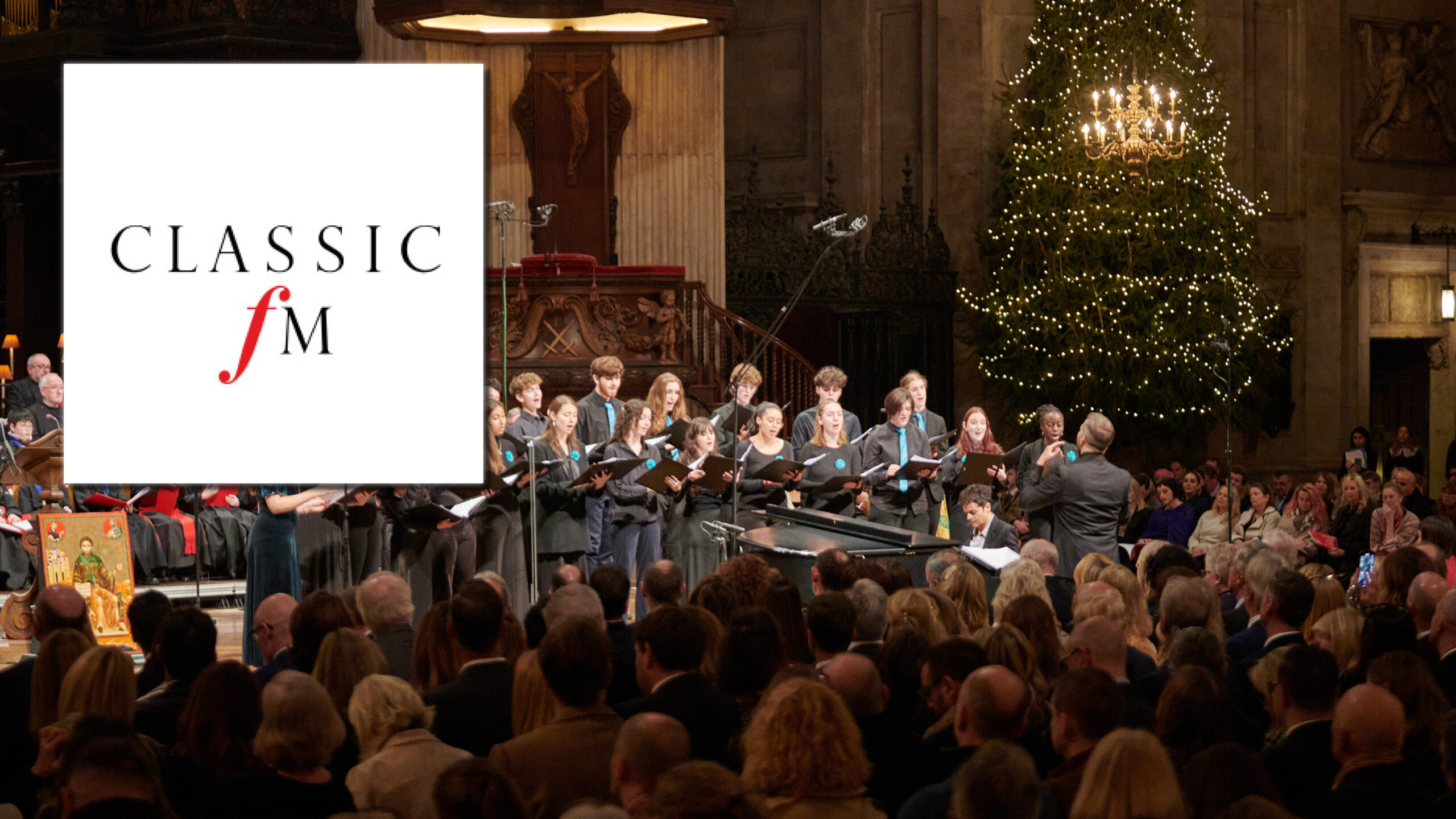 A white classic fm logo in the top left. Behind it, LYC Chamber Choir is singing, dressed in black with teal accessories, in a cathedral. There is a large Christmas tree behind the choir to the right. In the foreground, a congregation is watching.