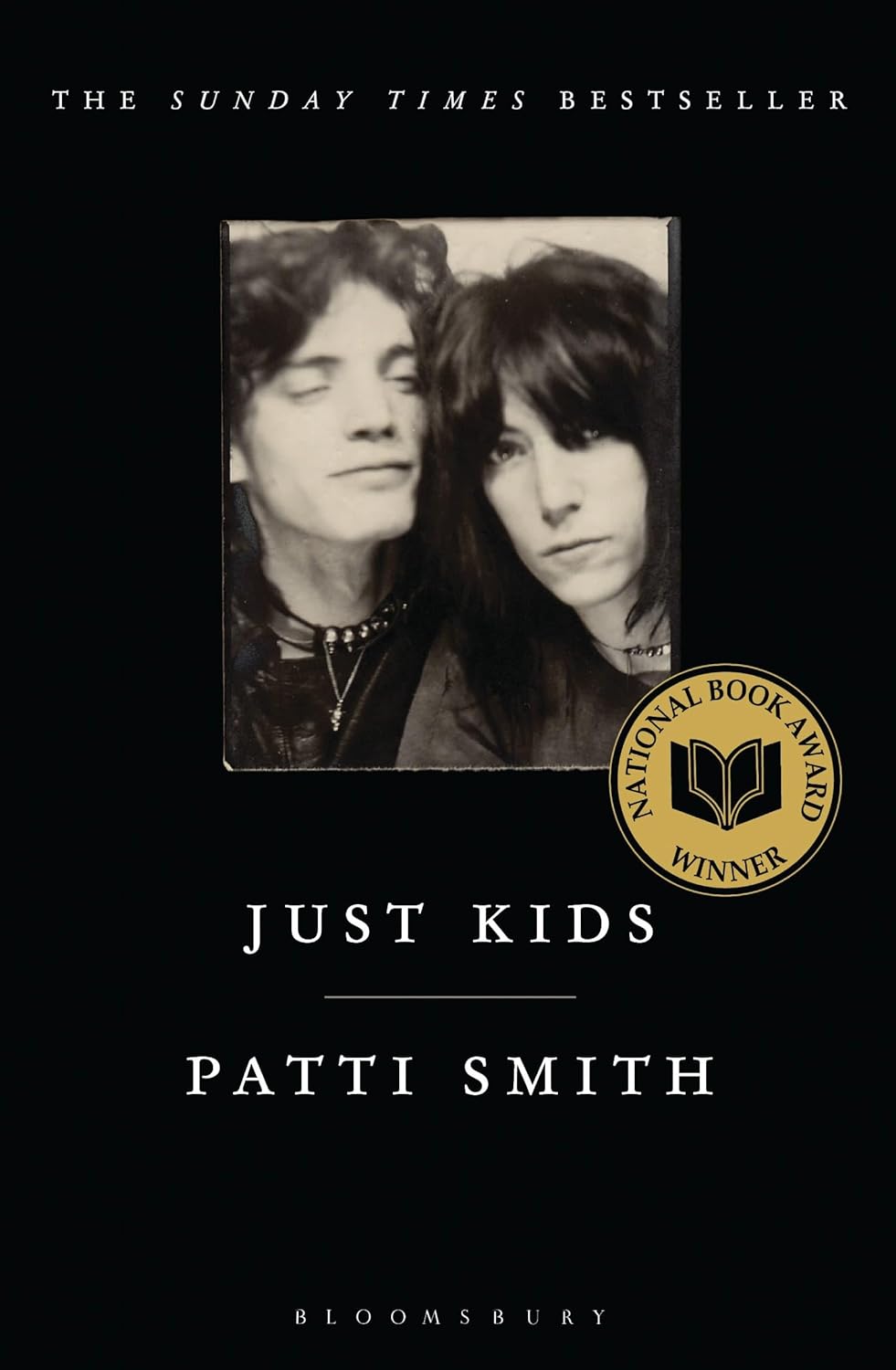 The front cover of Just Kids. A black background, with a square shaped black and white image in the centre of two young adults. There is a gold circle on the cover saying 'National Book Award winner'. White writing at the top of the cover says The Sunday Times Bestseller.