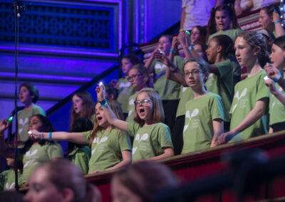 Several row of girls wearing green T shirts with an LYC logo. They are holding up finger torches.